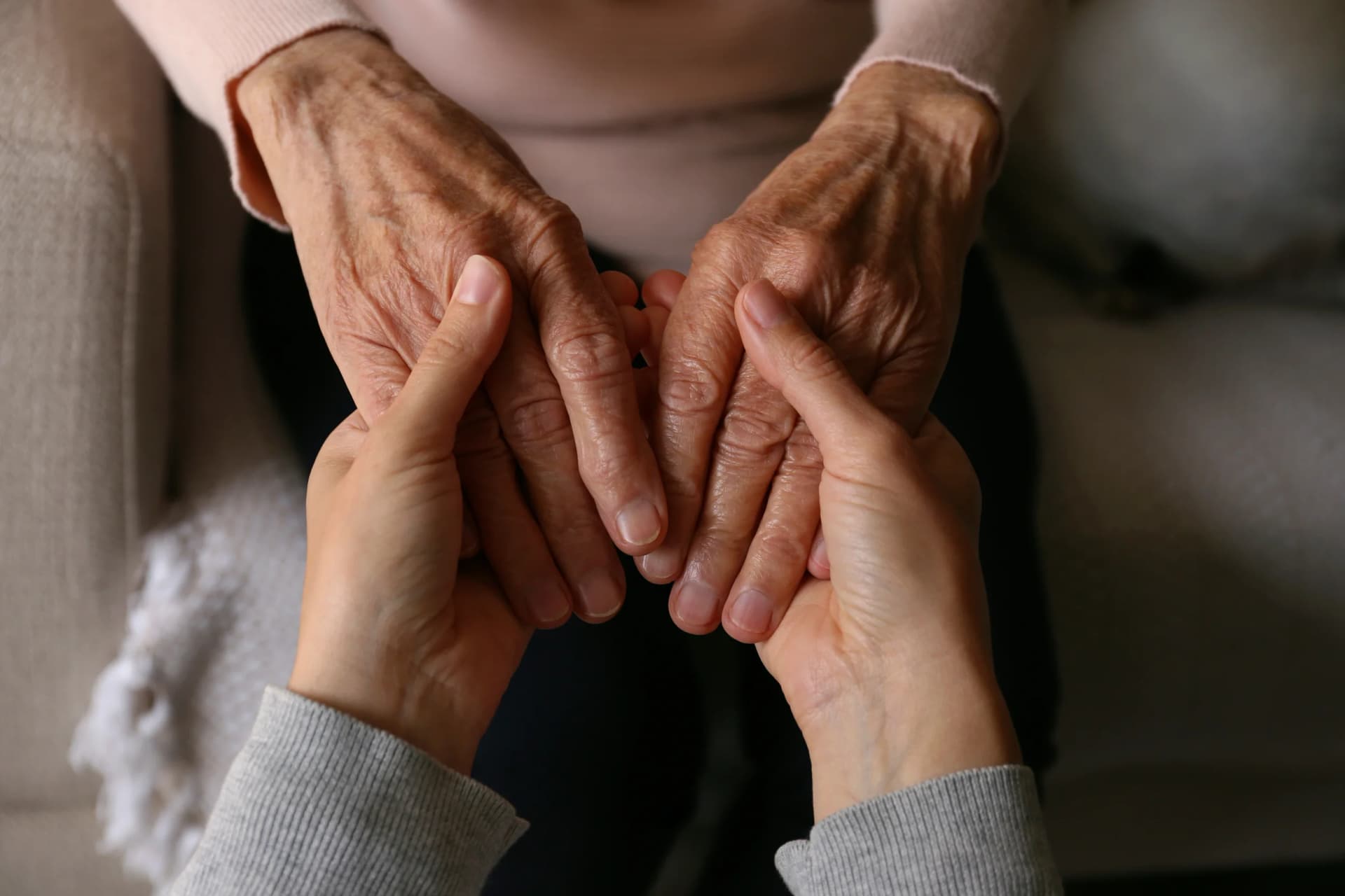 Cropped Shot Of Elderly Woman And Female Geriatric Social Worker Holding Hands. Women Of Different Age Comforting Each Other. Close Up, Background, Copy Space 1